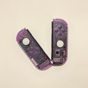 May include: A pair of purple Nintendo Switch Joy-Con controllers, disassembled and showing the internal components.