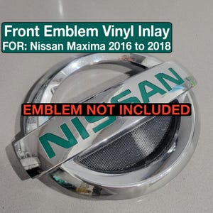 May include: Green vinyl inlay for a Nissan Maxima emblem. The emblem is chrome with a black background. The text "EMBLEM NOT INCLUDED" is printed in red on a white background.