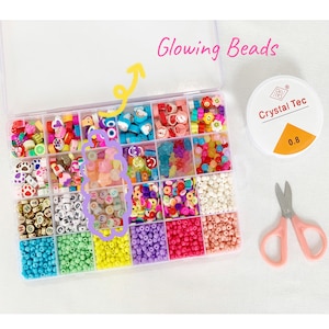 May include: A clear plastic storage box filled with colorful beads. The beads are organized into different compartments. The box includes a variety of shapes, including letters, animals, and hearts. The box also includes a small container of glowing beads labeled "Crystal Tec 0.8".