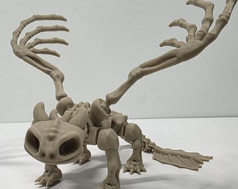 May include: A beige dragon skeleton figurine with large eye sockets and articulated limbs. The wings are skeletal, and the tail ends in a leaf-like shape. The figurine is posed on a white surface.
