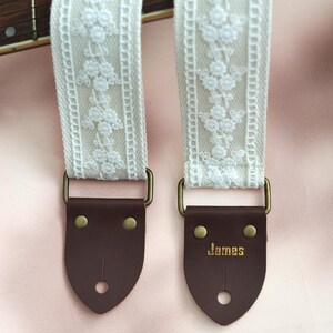 May include: White lace guitar strap with brown leather ends. The leather end has the word "James" embossed on it.