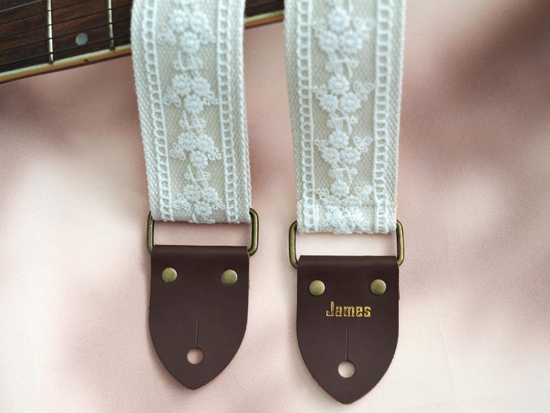 May include: White lace guitar strap with brown leather ends. The leather end has the word "James" embossed on it.