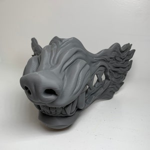 May include: A 3D printed gray wolf mask with a detailed, textured design. The mask features a snarling mouth with sharp teeth and a realistic wolf nose.