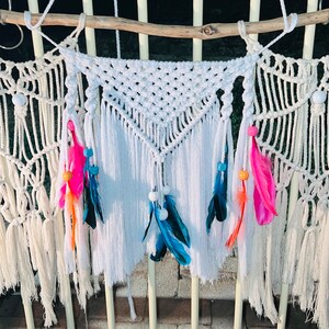 May include: Three white macrame wall hangings with fringe and colourful feathers and beads.