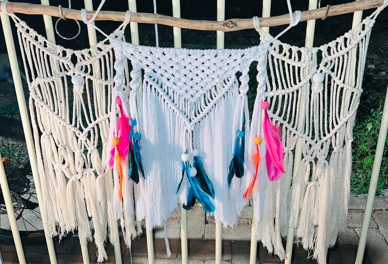 May include: Three white macrame wall hangings with fringe and colourful feathers and beads.