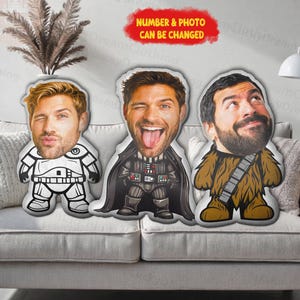 May include: Three custom-designed plush pillows featuring faces with cartoon bodies. One pillow is a Stormtrooper, one is Darth Vader, and the third is Chewbacca. The text "NUMBER & PHOTO CAN BE CHANGED" is in a red banner.