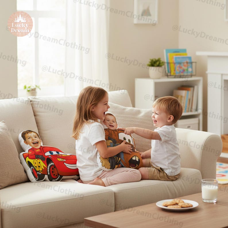 May include: Two custom-printed throw pillows featuring children's faces and cartoon car designs. One pillow showcases a red race car with the number 95, while the other depicts a brown tow truck. The pillows are on a cream-colored sofa.