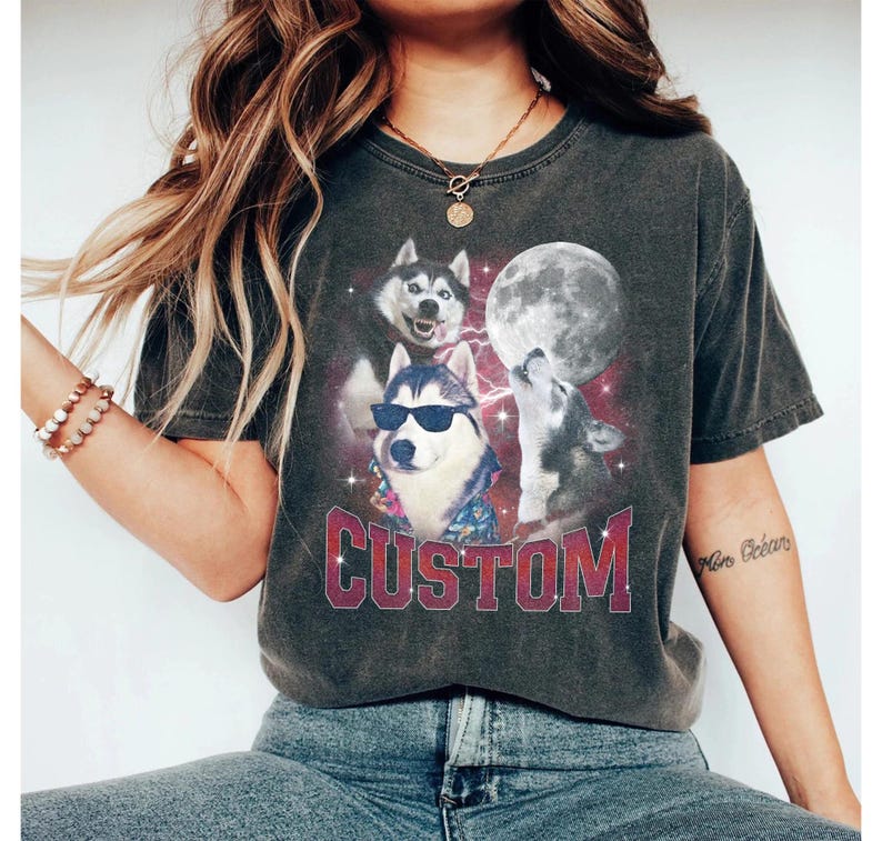 May include: A dark gray t-shirt with a graphic print of three cartoon huskies in front of a full moon. The huskies are wearing sunglasses and one is wearing a Hawaiian shirt. The text "CUSTOM" is printed in red below the huskies.