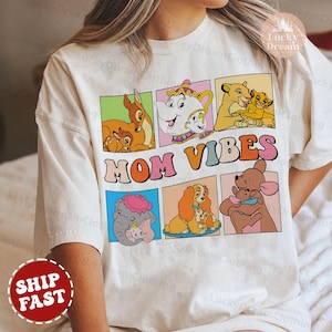 Puede incluir: Camiseta blanca con un estampado gráfico colorido de personajes de Disney. Los personajes están en cuadrados con el texto "MOM VIBES" en una fuente arcoíris.