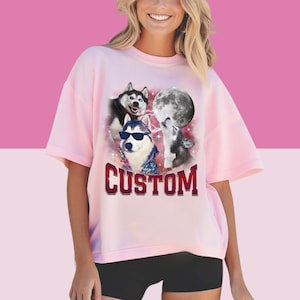 May include: Pink t-shirt with a graphic of three husky dogs howling at the moon. The text "CUSTOM" is printed below the image.