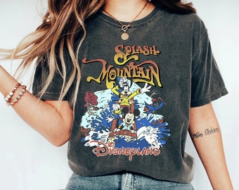 May include: A dark gray t-shirt with a vintage-style graphic of Mickey Mouse and Goofy on Splash Mountain at Disneyland. The text "Splash Mountain" and "Disneyland" are printed on the shirt.