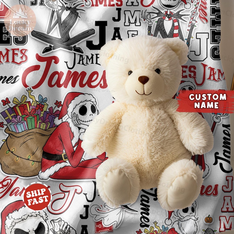 Puede incluir: Un oso de peluche color crema est&aacute; sobre una manta blanca con un dise&ntilde;o rojo y negro. La manta presenta el nombre "James" e im&aacute;genes de Pap&aacute; Noel y otros personajes. Una pancarta roja con "CUSTOM NAME" es visible.