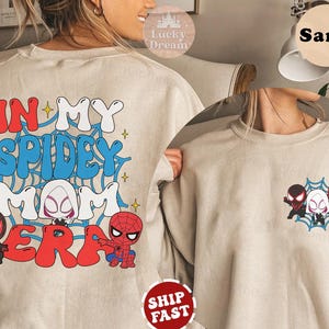 May include: A beige sweatshirt with the text "In My Spidey Mom Era" in red, blue, and white lettering. The sweatshirt features a graphic of Spider-Man characters, including Spider-Man, Spider-Gwen, and Miles Morales.