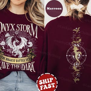 K&ouml;nnte beinhalten: Maroonfarbener Pullover mit einem wei&szlig;en Aufdruck eines Drachen und dem Text "ONYX STORM THE BIGGEST BATTLE YET BRAVE THE DARK".