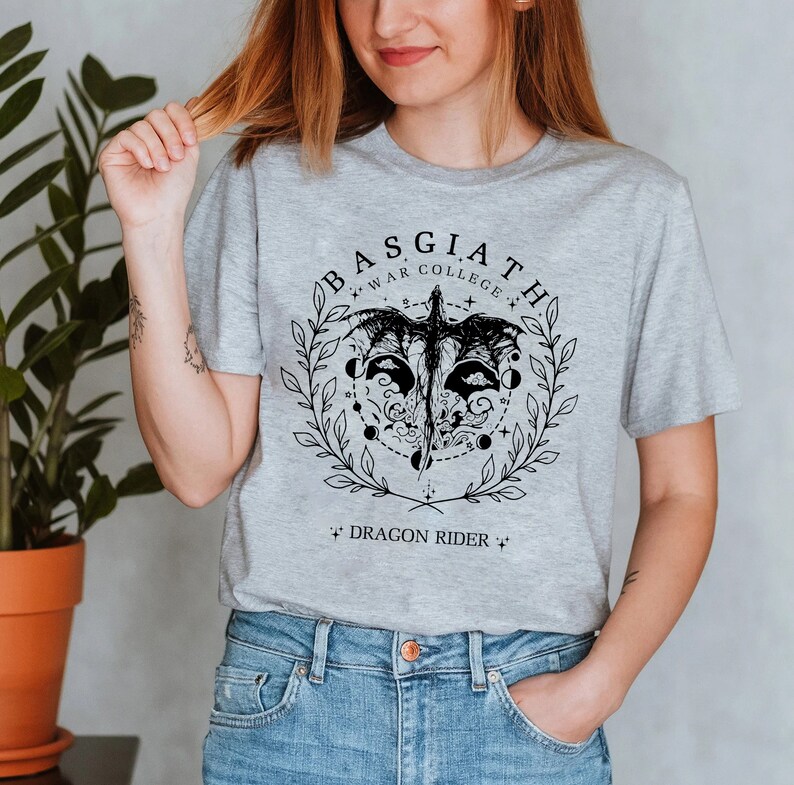 May include: Grey t-shirt with a black graphic design featuring a dragon with the text "BASGIATH WAR COLLEGE * DRAGON RIDER *"