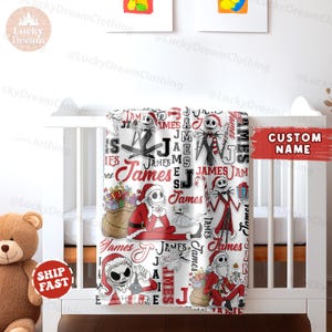 Puede incluir: Una manta de beb&eacute; blanca con un patr&oacute;n repetido de ilustraciones de Pap&aacute; Noel y Jack Skellington en rojo, negro y blanco. El nombre "James" tambi&eacute;n aparece en el dise&ntilde;o. La manta est&aacute; sobre una cuna blanca.