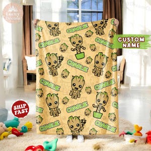 May include: A yellow and green fleece blanket with a repeating pattern of a cartoon character named "Groot" from the Guardians of the Galaxy movie franchise. The character is holding a small plant and the text "CHARLIE" is repeated throughout the blanket.