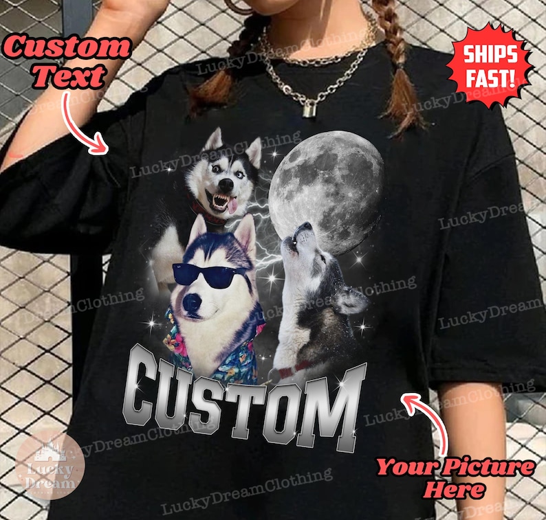 May include: Black t-shirt with a graphic of three husky dogs howling at the moon. The text "CUSTOM" is printed in silver on the shirt. The shirt is available for customization with a picture and text.