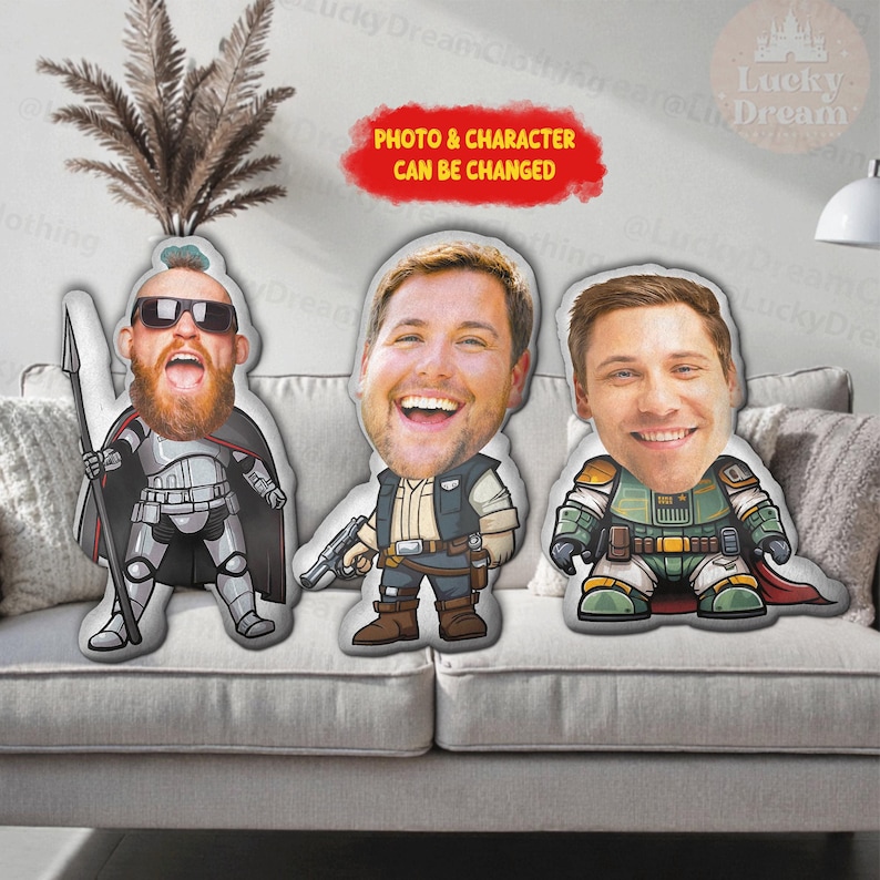 Puede incluir: Tres cojines de personajes personalizados con caras sonrientes, cada uno con un disfraz &uacute;nico. Los cojines est&aacute;n sobre un sof&aacute; gris. El texto "PHOTO & CHARACTER CAN BE CHANGED" est&aacute; en una burbuja roja.
