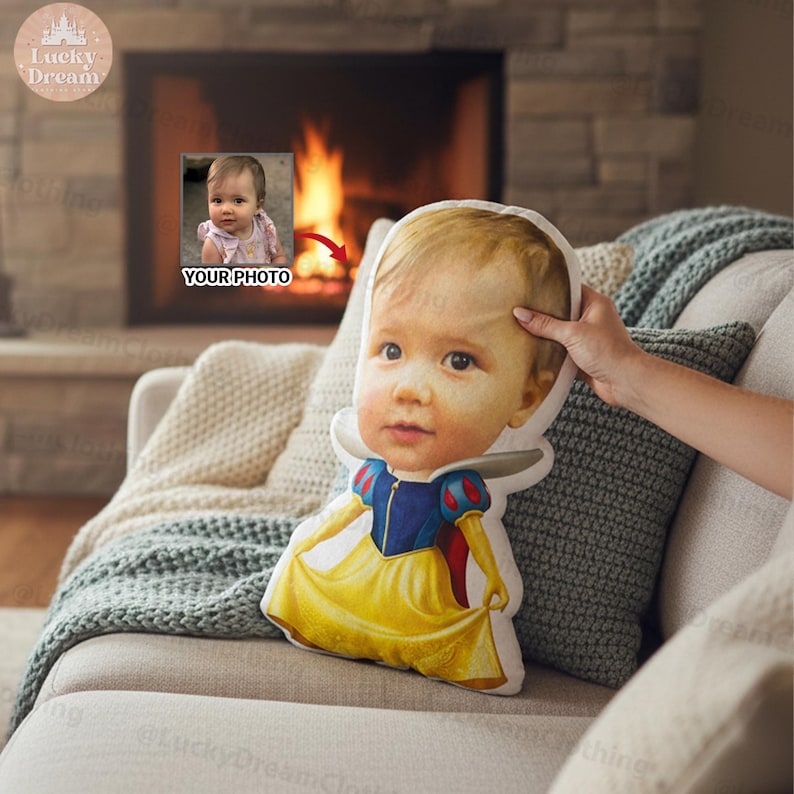 May include: A custom pillow featuring a baby's face, designed to resemble Snow White. The pillow has a yellow dress with blue and red accents. The words "YOUR PHOTO" are visible in the background.
