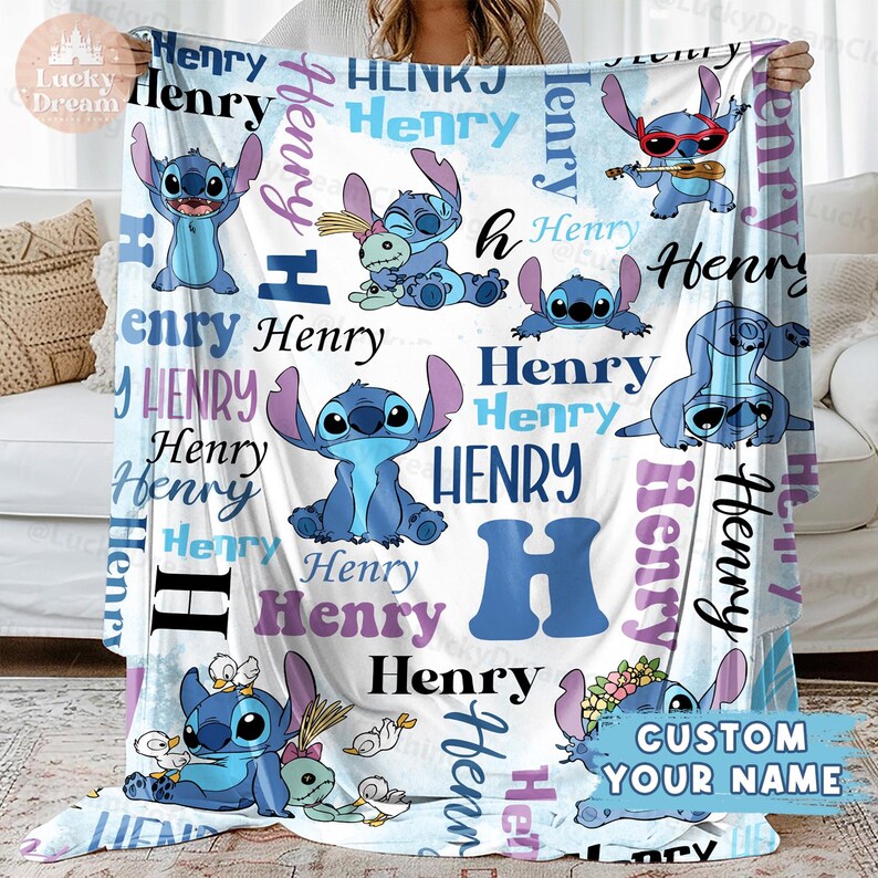 Puede incluir: Una manta de forro polar blanca con un patr&oacute;n azul y morado que presenta un personaje de dibujos animados llamado Stitch. La manta est&aacute; personalizada con el nombre "Henry" repetido en todo el dise&ntilde;o. El texto "CUSTOM YOUR NAME" tambi&eacute;n est&aacute; incluido en la manta.