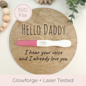 May include: A round wooden sign with the text "HELLO DADDY" and a pregnancy test with a positive result. The text below the test reads "I hear your voice and I already love you." The sign is laser engraved and tested.