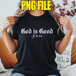 May include: Black t-shirt featuring the white text "God is Good" in a gothic font, with "All the time" in a script font below. The shirt has a crew neck.