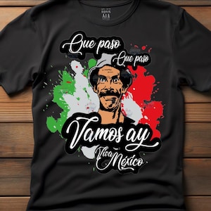 May include: Black t-shirt with a portrait of a man with a mustache and a hat, set against green, white, and red paint splatters. The shirt features the phrases "Que paso" and "Vamos ay Viva México" in white script.