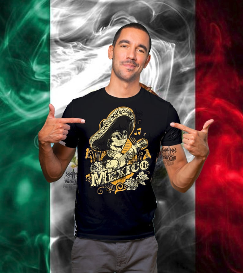May include: Black t-shirt featuring a cartoon character playing a guitar and wearing a sombrero. The design includes the word "Mexico" in a decorative font, with musical notes and floral accents. The background is a stylized Mexican flag.