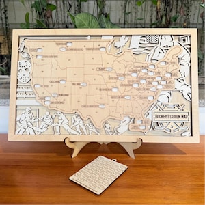 May include: A wooden Hockey Stadium Map of the United States, laser-cut with a light wood finish. The map features stadium locations, hockey-themed illustrations, and the text "HOCKEY STADIUM MAP". Includes a separate tag with hockey puck shapes.