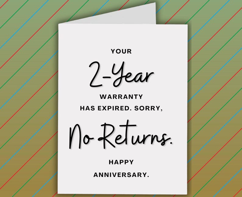 Pode incluir: Um cart&atilde;o branco com o texto "YOUR 2-Year WARRANTY HAS EXPIRED. SORRY, No Returns. HAPPY ANNIVERSARY." O cart&atilde;o tem um interior branco e est&aacute; colocado sobre um fundo com listras diagonais em verde, azul e vermelho.