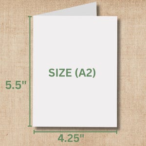 Op de afbeelding: Een witte A2-kaart met afmetingen van 14 cm bij 10,8 cm. De tekst "SIZE (A2)" is in het groen op de kaart gedrukt. De kaart is open en toont een leeg interieur.