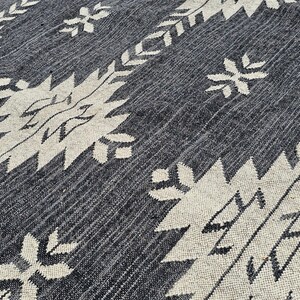 May include: A black and white patterned rug with a geometric design. The rug has a textured surface and a subtle sheen.