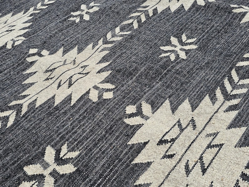 May include: A black and white patterned rug with a geometric design. The rug has a textured surface and a subtle sheen.