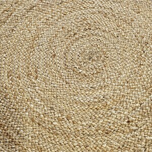 Peut inclure: Gros plan sur un tapis rond en jute. Le tapis en fibre naturelle pr&eacute;sente un motif en spirale, avec des brins &eacute;troitement tiss&eacute;s cr&eacute;ant une surface textur&eacute;e. La palette de couleurs neutres du tapis le rend adapt&eacute; &agrave; divers styles d'int&eacute;rieur.