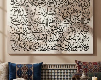 May include: Large canvas art featuring black Arabic calligraphy script on a cream-colored background. The artwork hangs above a sofa with decorative pillows and a wooden table. The room has a warm, inviting atmosphere.