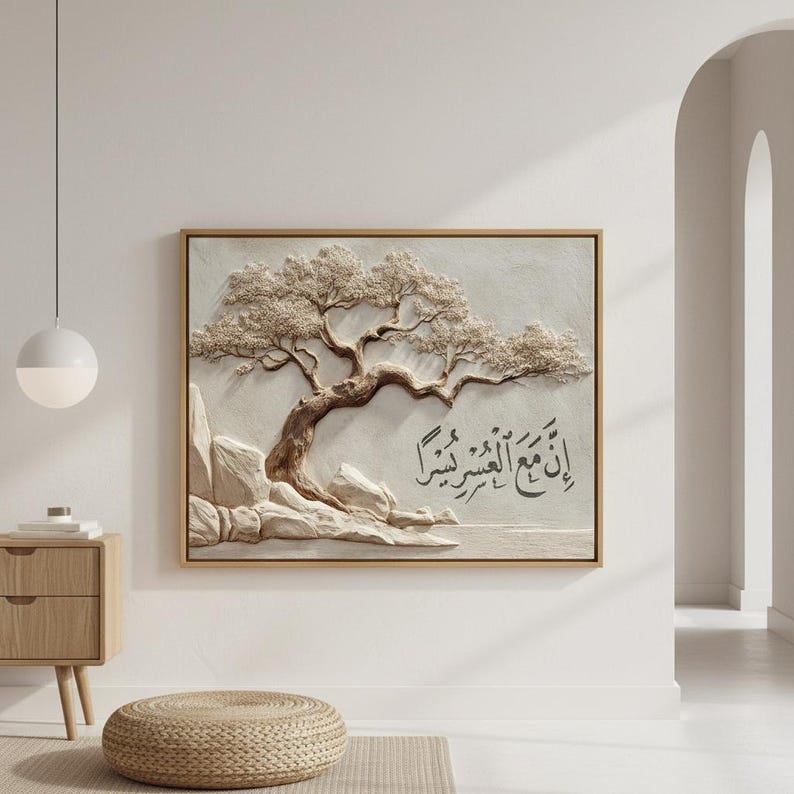 May include: A framed, textured artwork featuring a detailed relief of a tree with a winding trunk and full, textured foliage. The artwork includes Arabic calligraphy and is set against a neutral background, framed in a light wood.