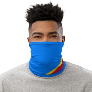 May include: A blue face covering with a yellow and red diagonal stripe design. The mask is being worn by a person with short, dark hair.