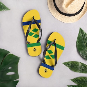 May include: A pair of yellow flip-flops with a blue, green, and yellow design. The flip-flops have a black strap and a small logo on the bottom.