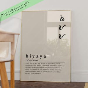 May include: A beige printable art print with a gold frame. The print features the word "biyaya" in black text with a definition in smaller black text. The word "biyaya" is defined as a gift that brings joy, peace, or well-being, often unexpected but deeply cherished. The print also includes a symbol of three stylized hearts.