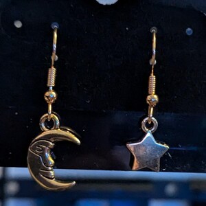 Moon and Star paired Celestial Earrings, dangling on a Fishhook style earing hook.