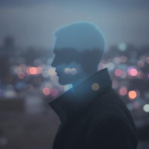 May include: A silhouette of a person against a blurred cityscape at dusk. The word "INVISIBILITY" is displayed in white at the top. The image has a moody, atmospheric feel with soft focus and bokeh lights in the background.