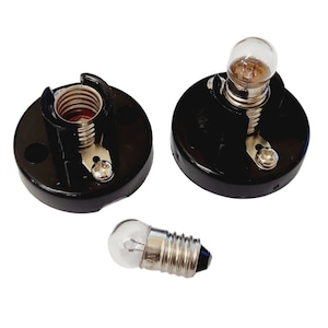 May include: Two black ceramic light bulb sockets with a single light bulb. The light bulb is clear glass with a silver metal base.