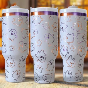 May include: Three white insulated tumblers with handles, decorated with a repeating pattern of cartoon ghosts in various shapes and sizes. The tumblers have a purple and copper-colored trim and a white lid. The background features pumpkins and fall foliage.