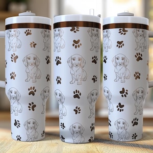 Könnte beinhalten: Drei weiße Edelstahl-Reisebecher mit braunem Deckel und einem schwarzen Dackel-Pfotenabdruck-Design. Die Becher haben einen Griff an der Seite und sind perfekt für Kaffee, Tee oder andere Getränke.