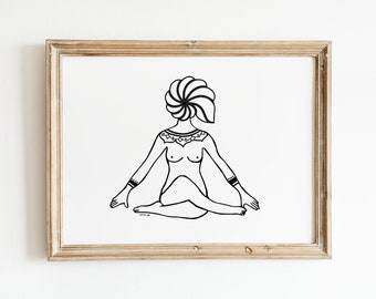 May include: Black and white line art print of a figure in a seated yoga pose, framed in a light brown wooden frame. The figure has a stylized head and detailed upper body ornamentation. The artwork is on a white background.