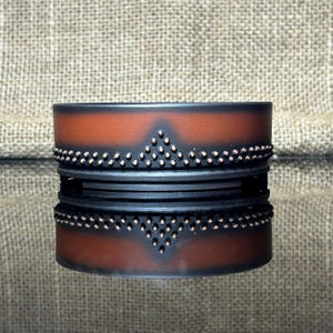May include: A black and brown ceramic planter with a decorative copper dot pattern around the rim.