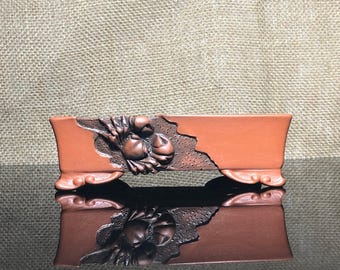 May include: A rectangular terracotta bonsai pot with a raised design of a crab on the side. The pot has three legs and a reddish-brown glaze.
