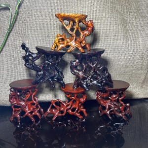 May include: Set of five wooden display stands, each with a unique, intricate branch-like design. The stands are made of dark brown, reddish-brown, and light brown wood. They are arranged in a pyramid shape, with the largest stand at the bottom and the smallest stand at the top.