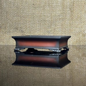 May include: A rectangular bonsai pot featuring a dark charcoal grey rim and base with a gradient of burnt orange and brown across the centre. The pot is supported by four small, ornate feet and has a smooth, matte finish on its exterior surface.